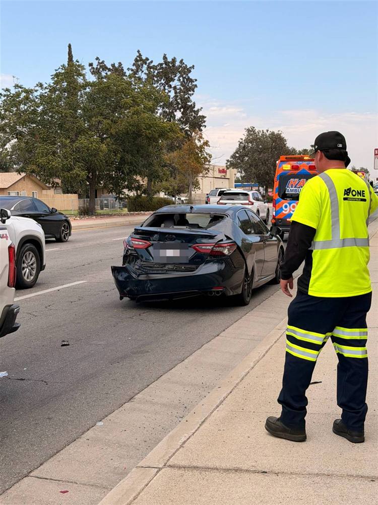 Black sedan with rear-end damage and an ambulance behind it