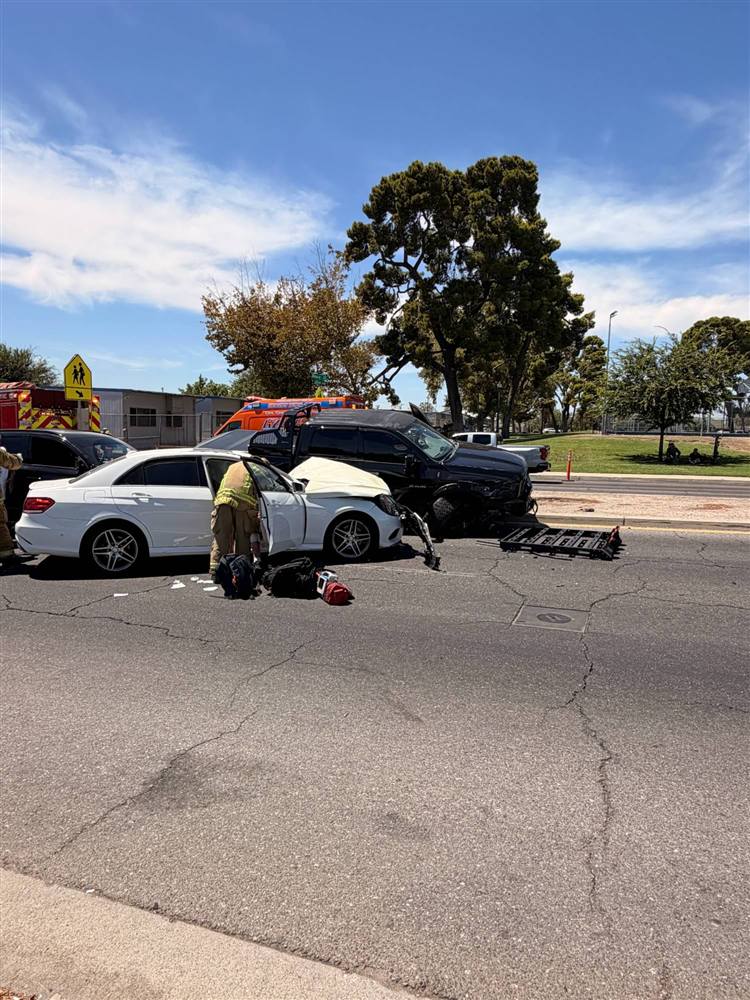Head-on collision between a white sedan and a pickup with firefighters helping